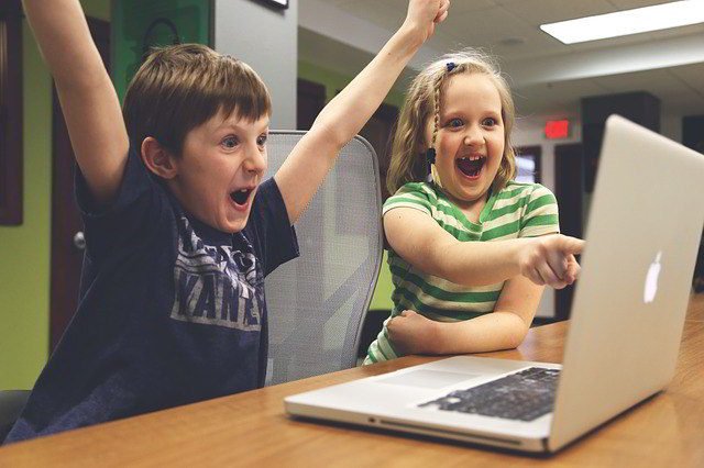 Teaching with technology - children using laptop computer enthusiastically