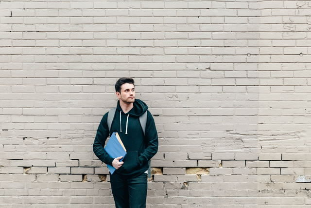 young college student leaning against wall