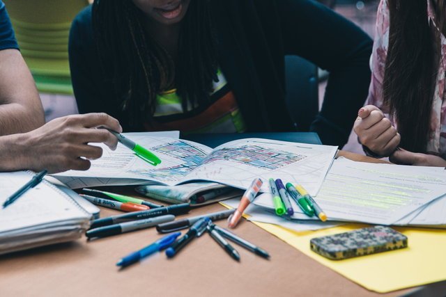 Students making notes on notebook with coloured pens.