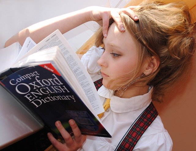 young girl studying english words from dictionary